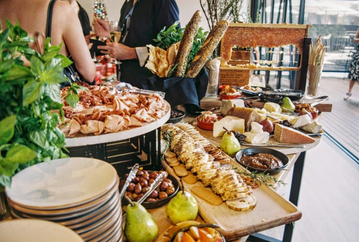 Gäste bedienen sich an einem Buffet mit Brot, Käse und Aufschnitt