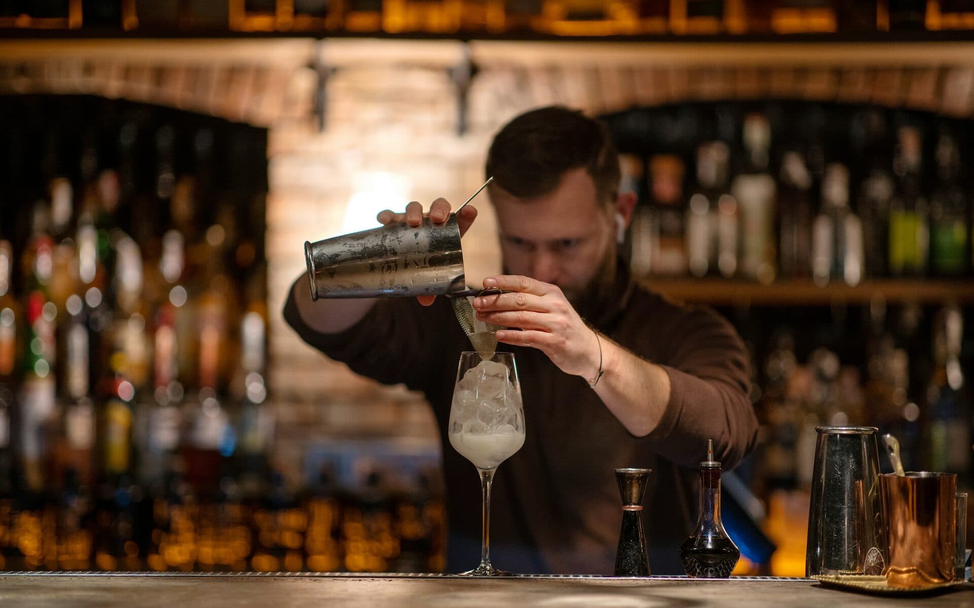 Barkeeper gießt einen Cocktail aus dem Shaker in ein Glas